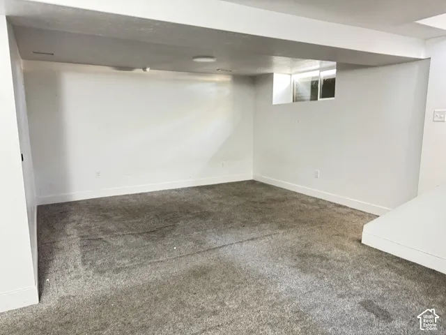 Recessed overhead lighting, gray carpeting, white painted walls, and a window well