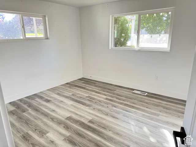 Wood-finish flooring, white walls, and two windows with white trim