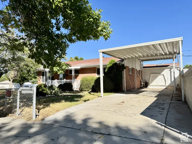 Brick exterior with a covered carport, concrete driveway, and front yard landscaping