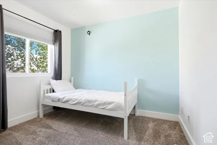 Window with horizontal blinds, light blue accent wall, white walls, and carpet flooring