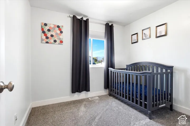 Carpeted room with a window featuring dark drapery