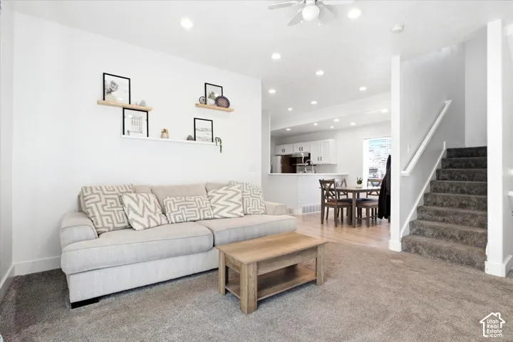 Recessed lighting illuminates the living area, featuring a ceiling fan and carpet flooring