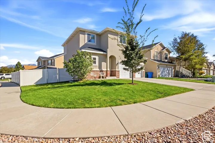 Two-story stucco exterior with an arched entry, prominent front lawn, and attached garage