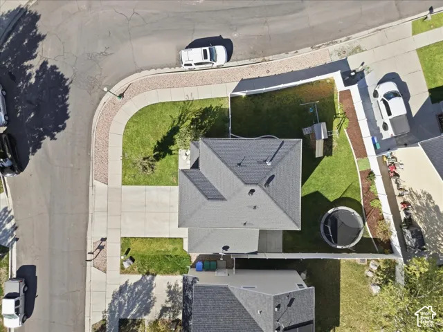 Corner lot with concrete driveway, expansive grassy areas, and mature landscaping