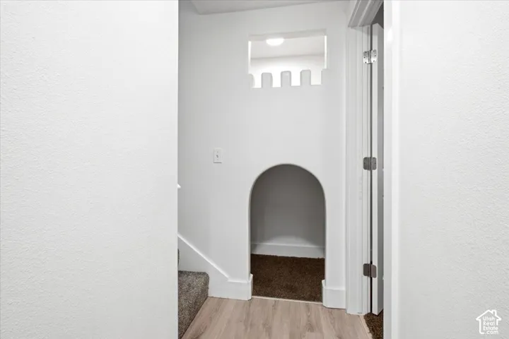 Archway cut-out with castle-themed trim, wood-finish flooring, and white painted walls