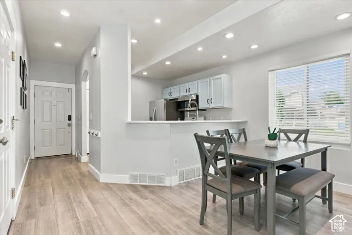 Wood-finish flooring throughout, recessed ceiling lighting, kitchen with light blue cabinetry, stainless steel appliances, and a pass-through counter