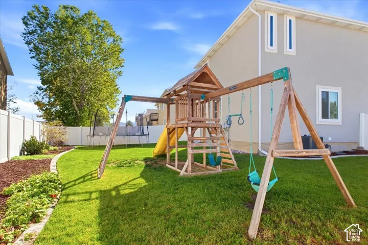 Expansive backyard featuring a manicured lawn, established landscaping, and a privacy fence