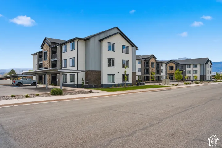 Modern exterior architecture featuring a multi-story design, stone accents, horizontal siding, and a covered parking structure