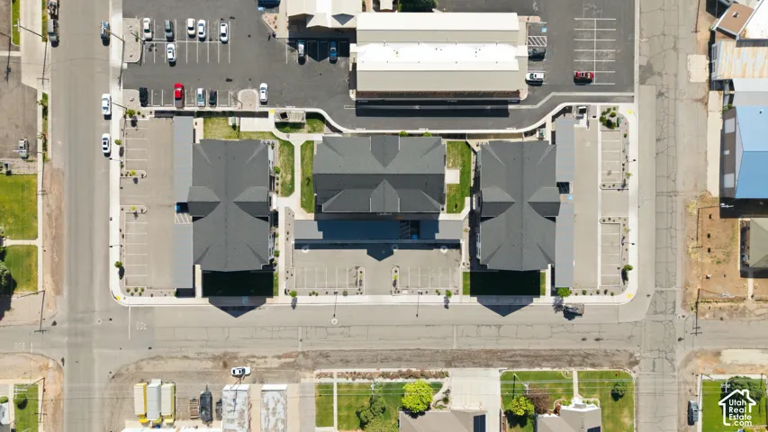 Multiple buildings with dark roofing, surrounded by paved parking areas