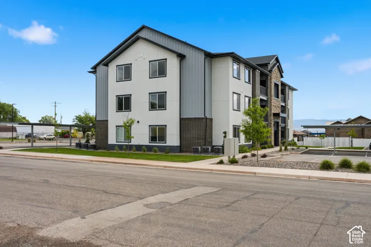 Modern multi-story building featuring a blend of white siding, dark gray panels, and stone accents