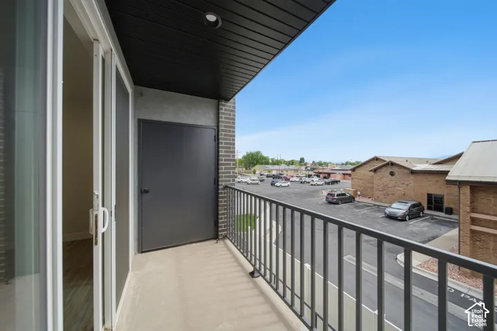 Private balcony with a concrete surface, black metal railing, and a dark exterior storage door