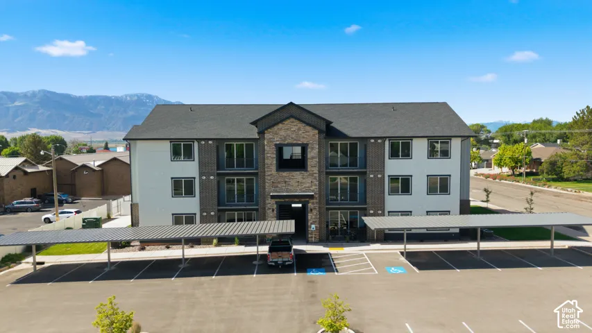 Modern multi-story structure featuring a stone and siding exterior, multiple windows, and a dark shingle roof
