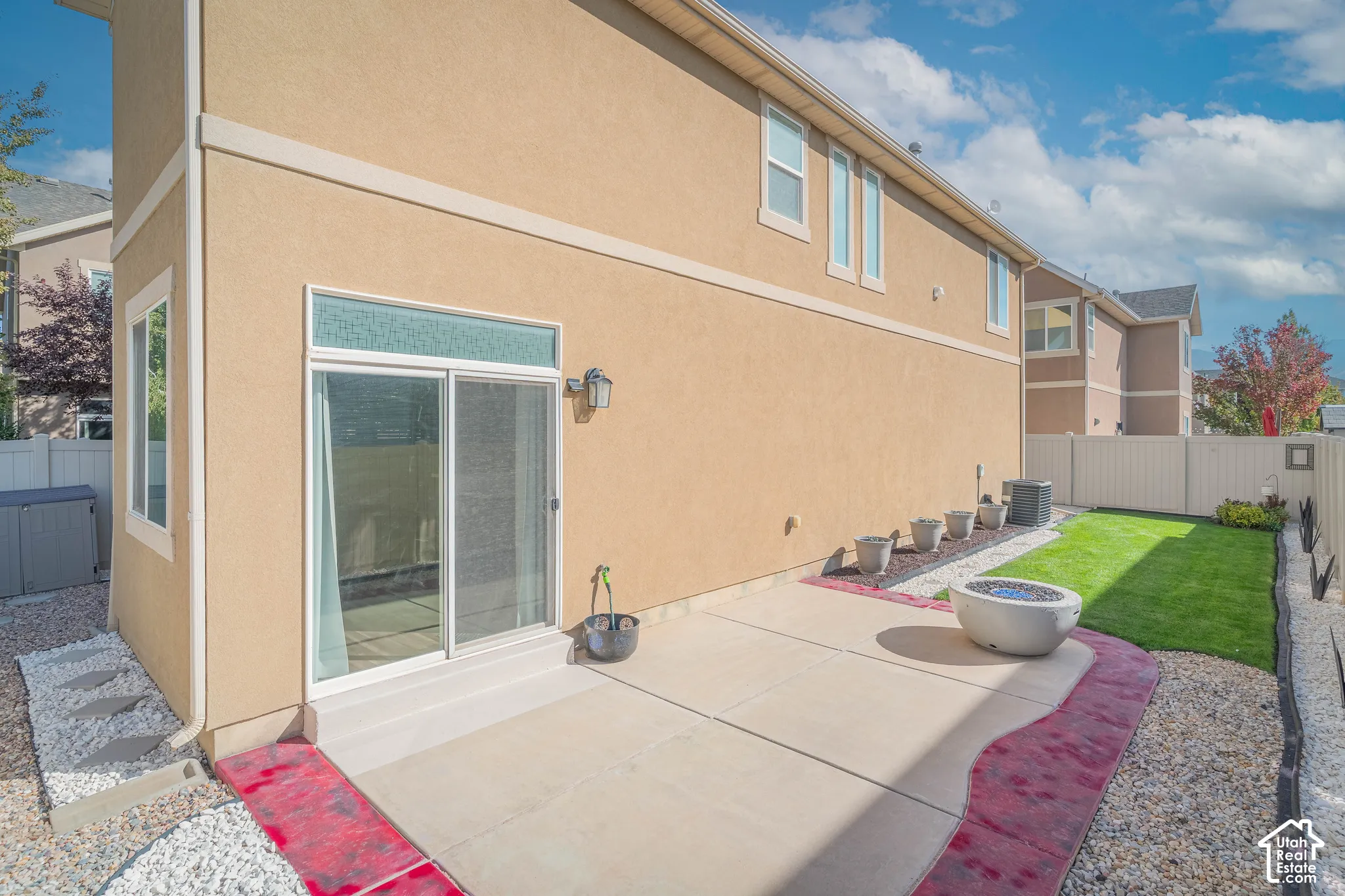 Patio area with concrete slab, gravel landscaping, and a manicured lawn