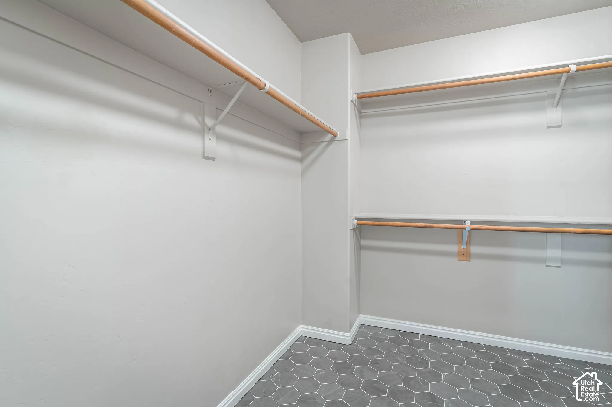 Hexagonal floor tiling, white walls, and built-in closet rods