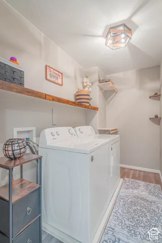 Dedicated laundry area featuring a flush mount light fixture, wood-finish flooring, and open shelving