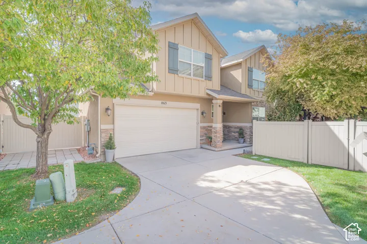 Two-story exterior with light-toned siding, stone accents, two-car garage, covered entry, and a paved driveway