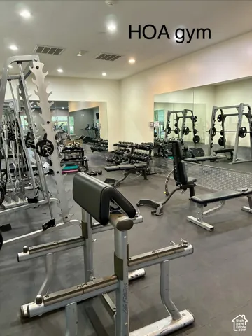 Fitness center with rubber flooring, extensive mirror walls, and recessed lighting