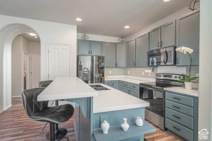 Kitchen featuring a two-tier island with white countertops, blue cabinetry, stainless steel appliances, and recessed lighting