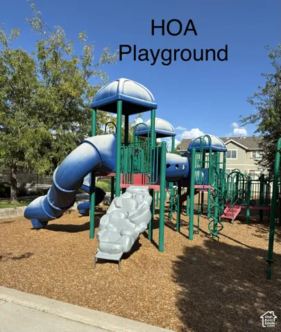 Community playground featuring a multi-level play structure with tube slides, open slides, and climbing elements