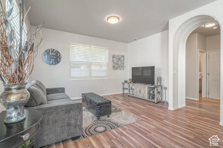 Wood-finish flooring, overhead lighting, arched doorway, and window with blinds