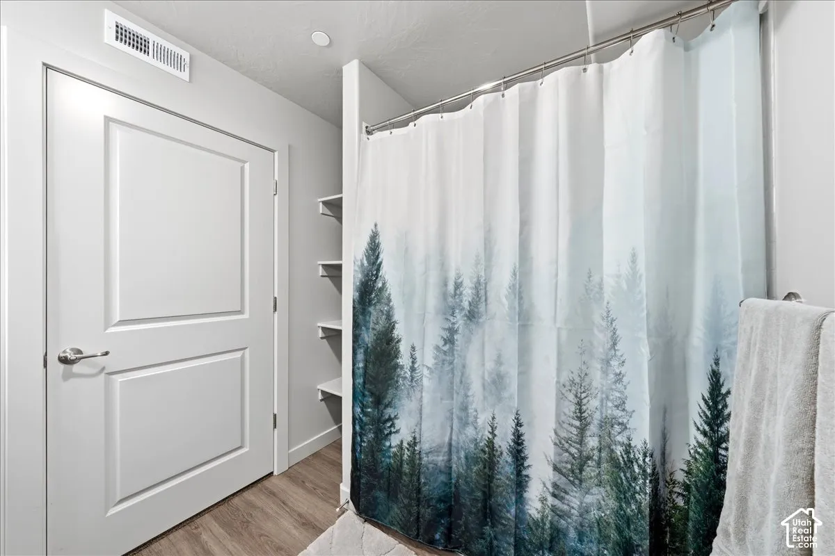 Wood-finish flooring, recessed lighting, built-in shelving, and a panel door with brushed nickel hardware