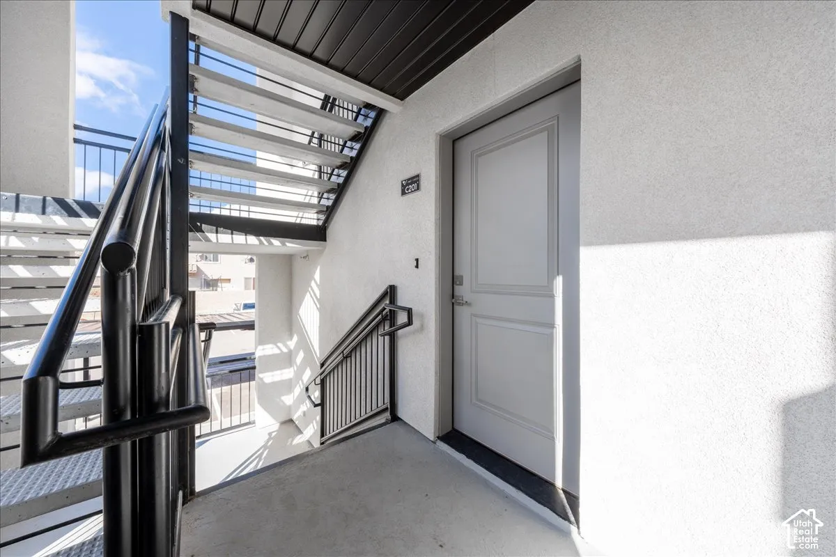 Exterior entry with panel door, black metal handrails, and concrete stairs