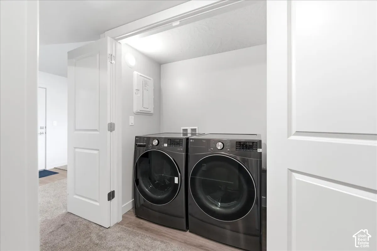 Dedicated laundry closet with light gray walls and wood-finish flooring