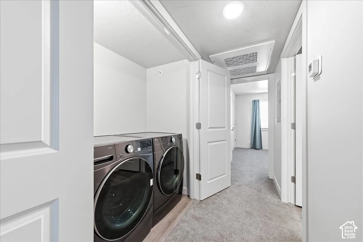 Dedicated laundry space featuring a side-by-side washer and dryer set, recessed lighting, and wood-finish flooring