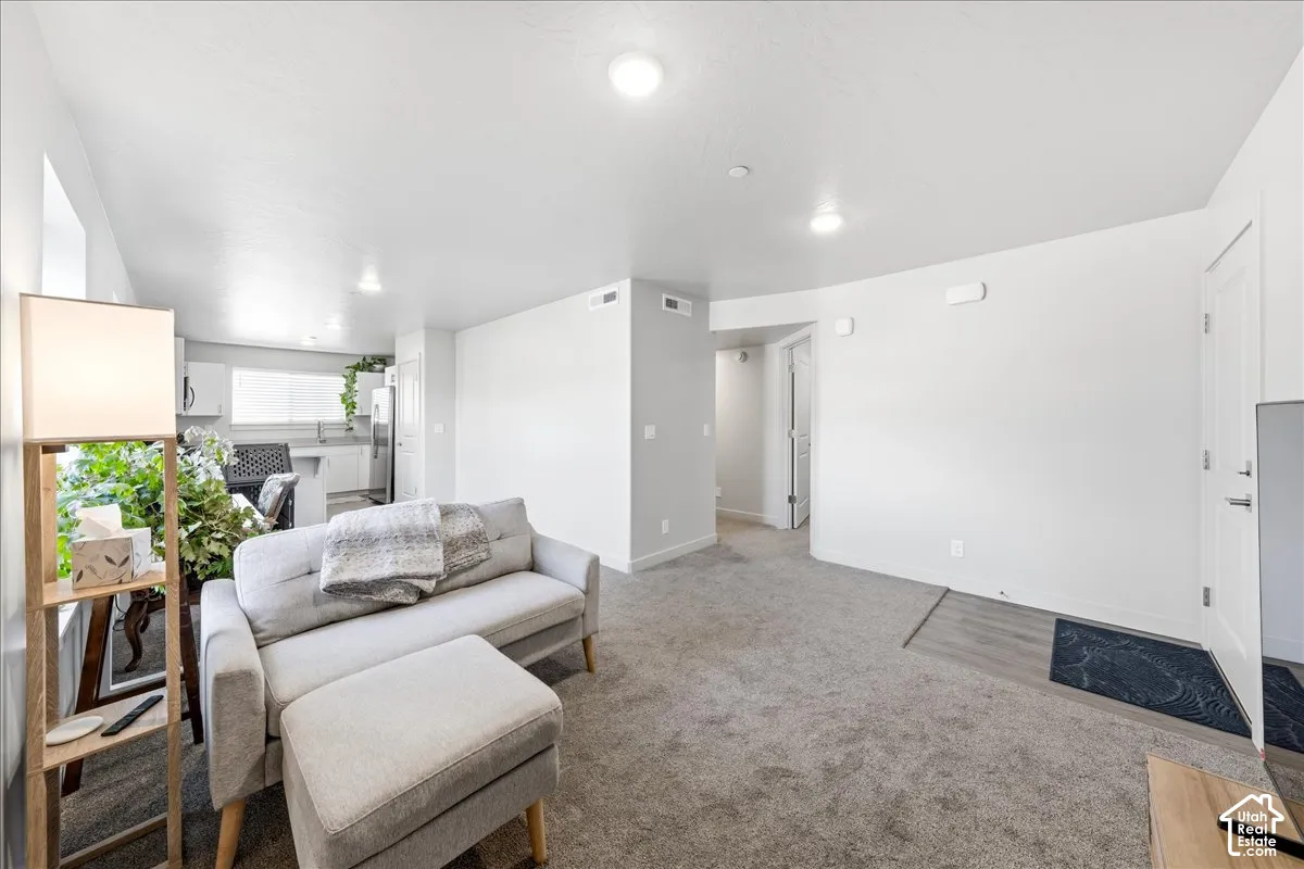 Recessed lighting, light gray wall finishes, light gray carpeting, wood-finish flooring at entry, and white interior doors