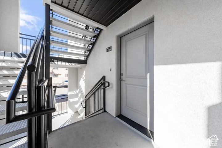 Exterior entry with panel door, black metal handrails, and concrete stairs