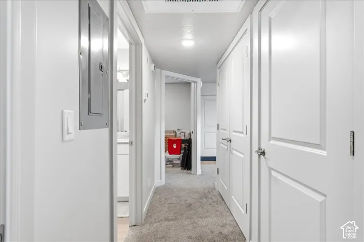 Hallway with light gray carpeting, recessed ceiling lighting, and multiple paneled doors