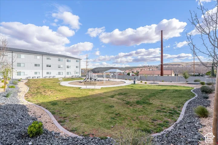 Landscaped community area featuring a green lawn, paved pathways, and a playground structure