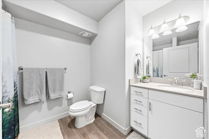 White vanity with brushed nickel hardware, light-toned countertop, rectangular mirror, and a three-light fixture