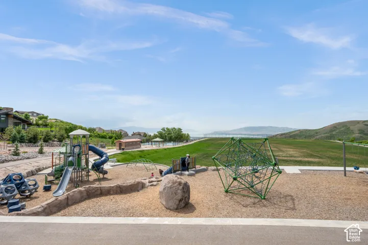 Community playground with diverse play structures, wood chip surfacing, and expansive green spaces
