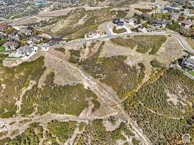 Expansive undeveloped land with varied topography, surrounded by established residences and paved roads