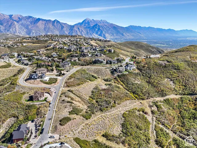 Expansive mountain backdrop with a wide valley floor, winding paved roads, and residential properties situated on hillsides