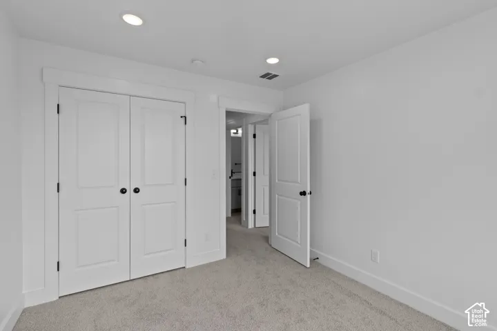 Recessed ceiling lighting, white interior doors with matte black hardware, light-toned carpeting, and crisp white wall finishes
