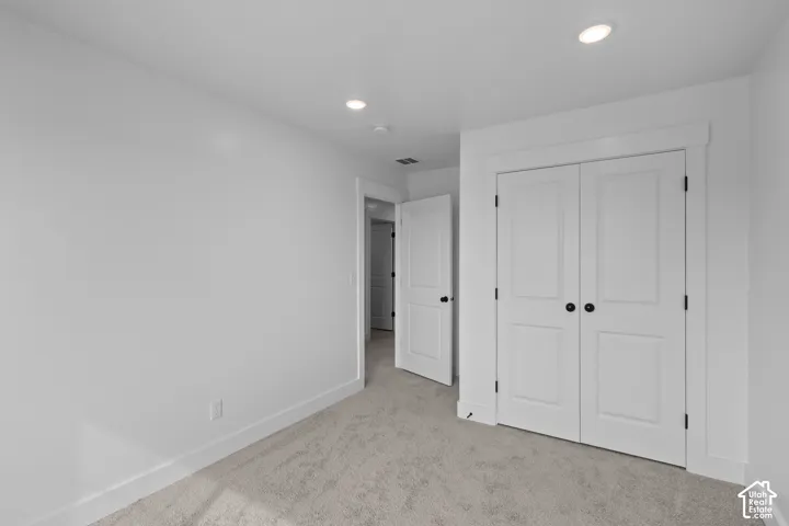 Recessed lighting, white trim, paneled doors with black hardware, and neutral carpeting