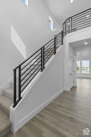 Two-story entryway with high ceilings, contemporary black metal railings, carpeted stairs, and wood-finish flooring