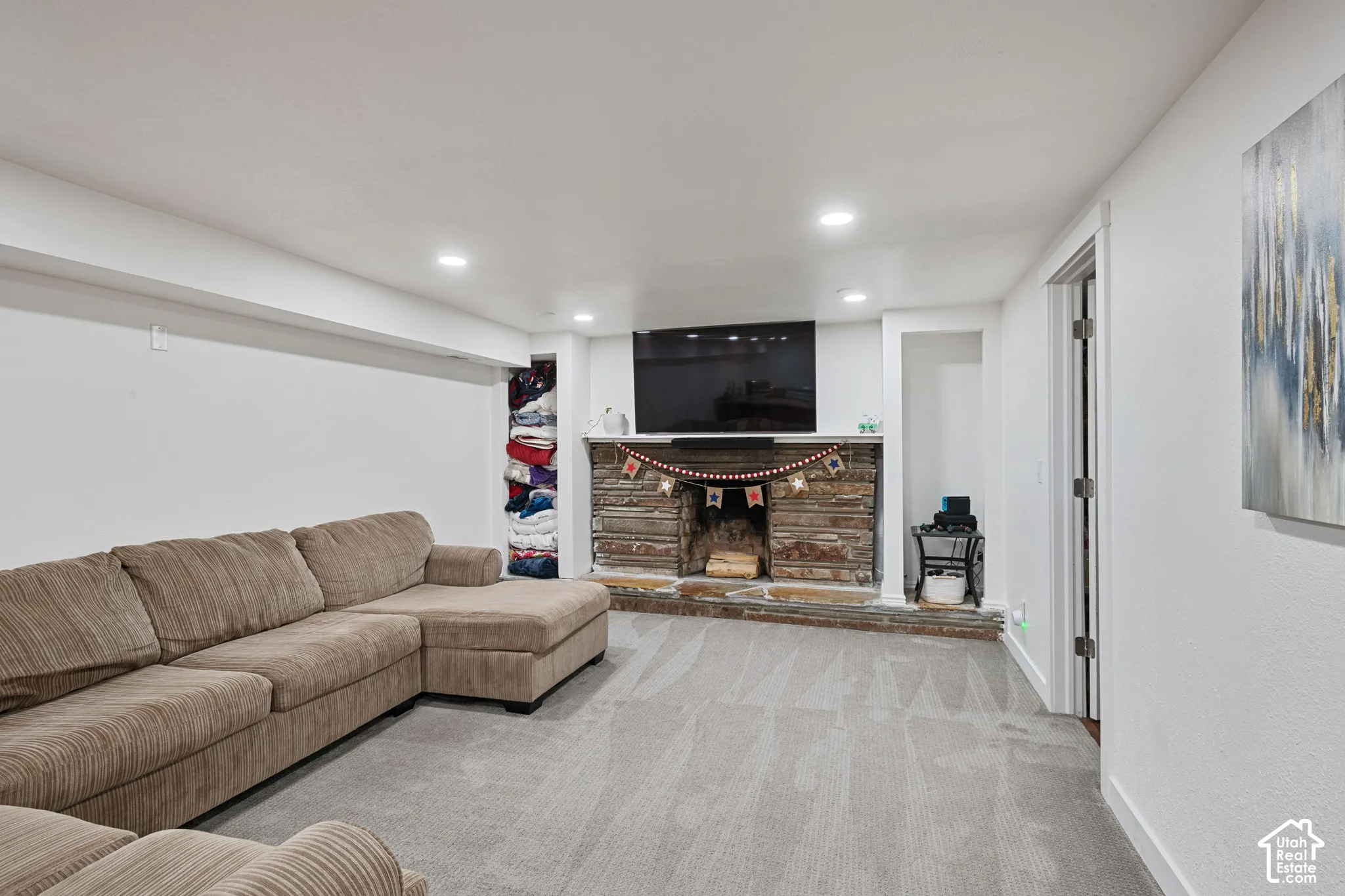 Stone-clad fireplace with a raised hearth, recessed lighting, carpeted flooring, and a built-in alcove