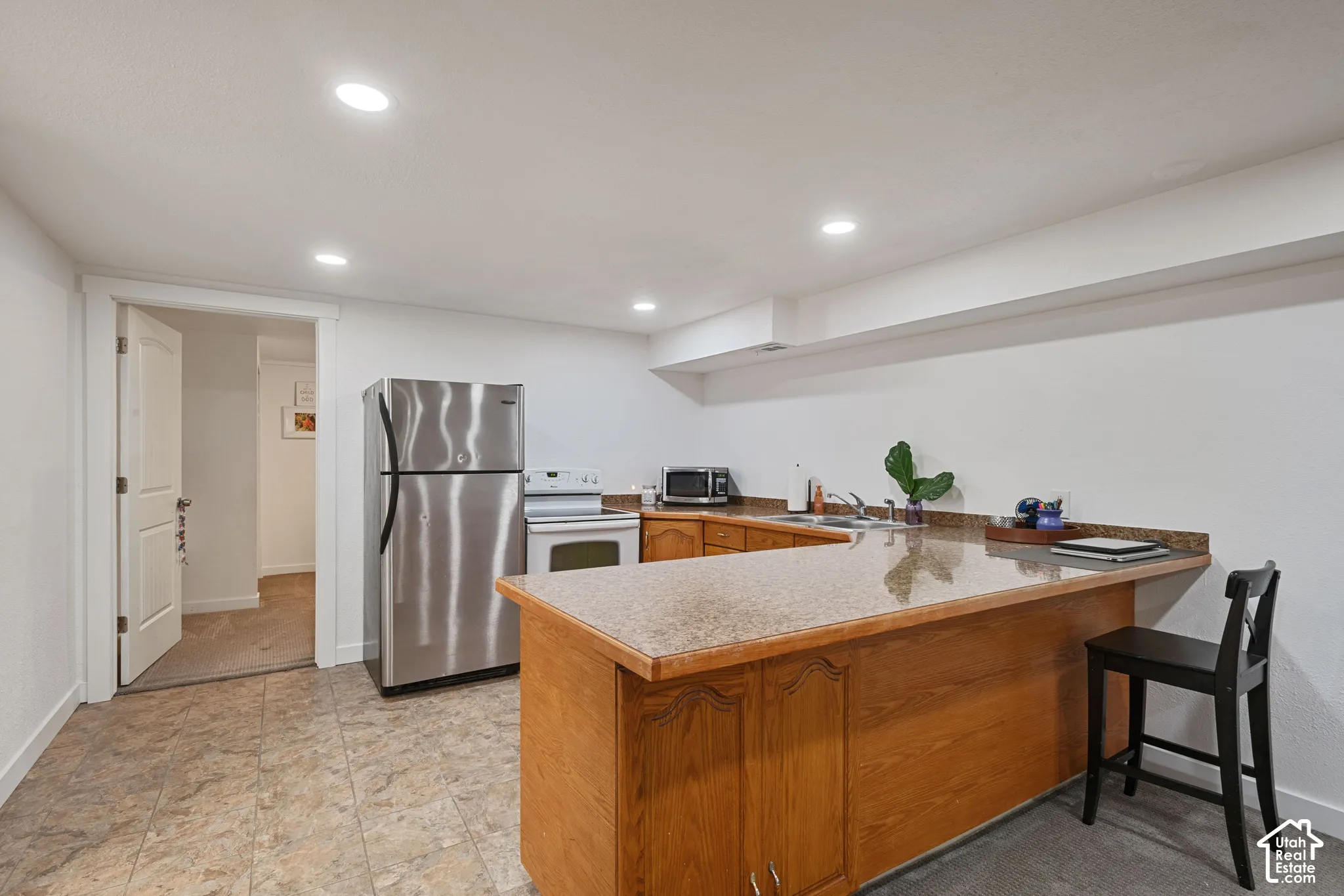 U-shaped kitchen with wood cabinetry, stainless steel refrigerator, white electric range, and recessed lighting