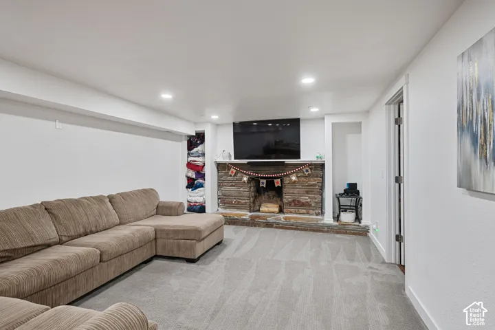 Stone-clad fireplace with a raised hearth, recessed lighting, carpeted flooring, and a built-in alcove