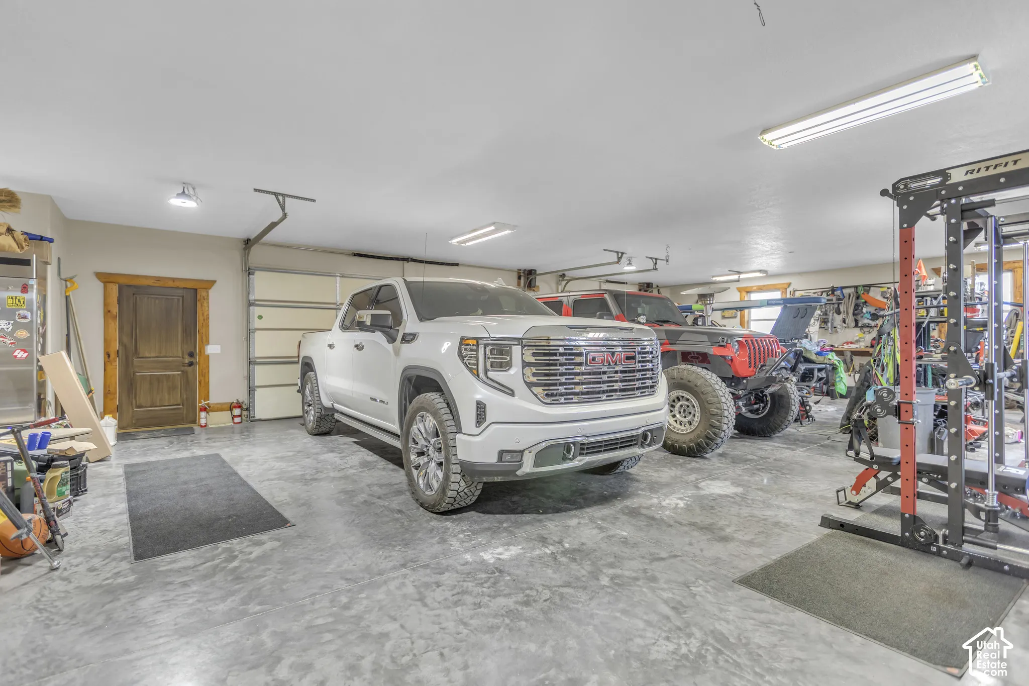 Spacious garage with textured concrete flooring, multiple overhead fluorescent light fixtures, and a wood-paneled overhead garage door