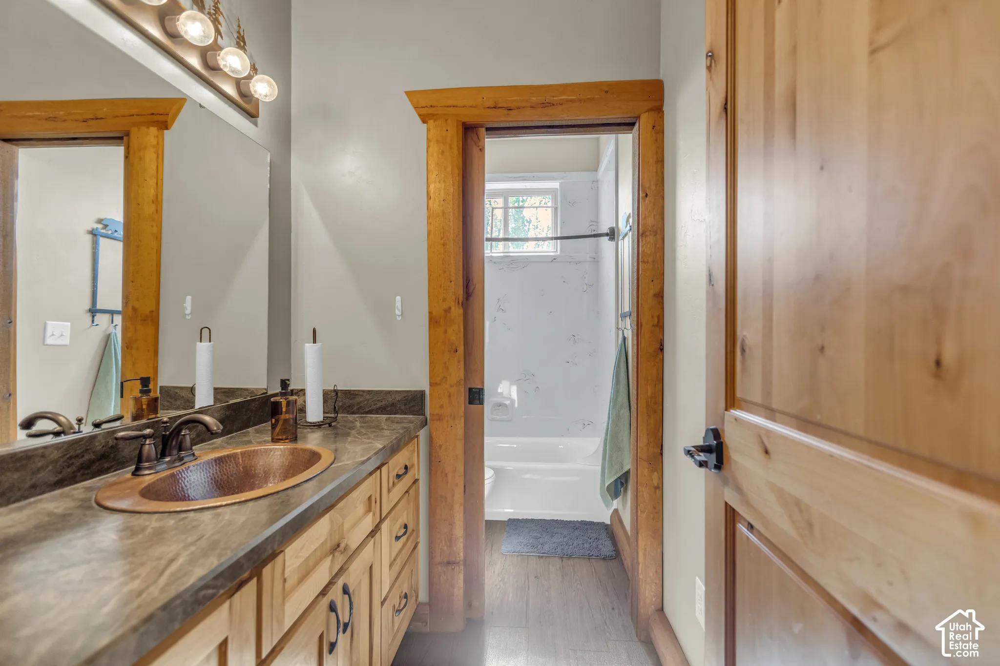 Wood-finish vanity with an integrated copper-tone basin sink and bronze-tone faucet