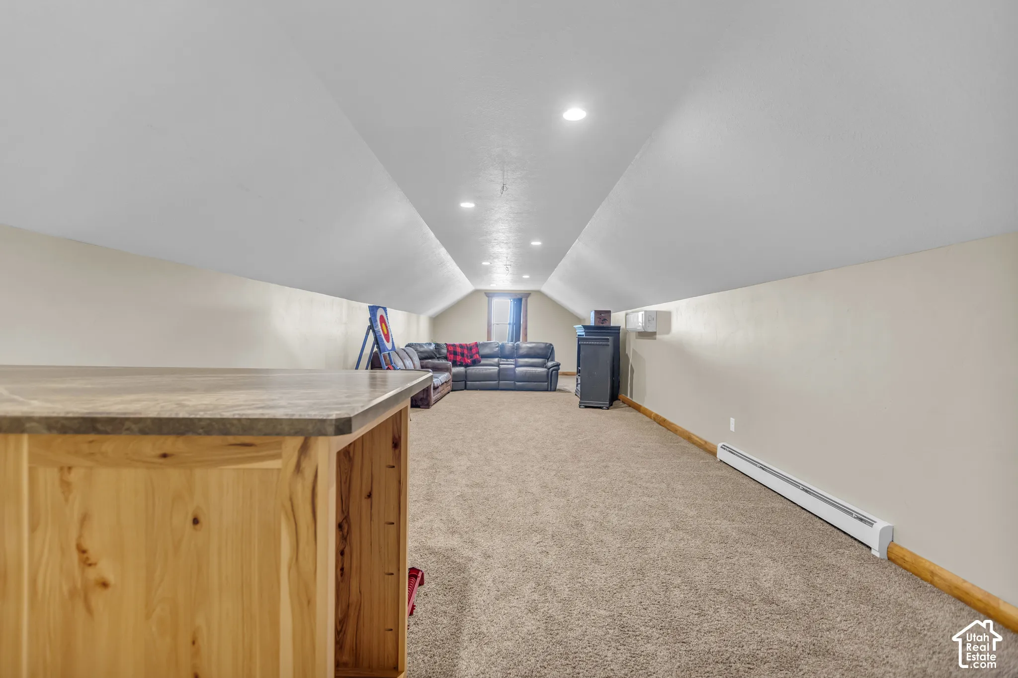 Carpeted flooring, recessed lighting, baseboard heating, window, and a built-in wood-finish half-wall with countertop