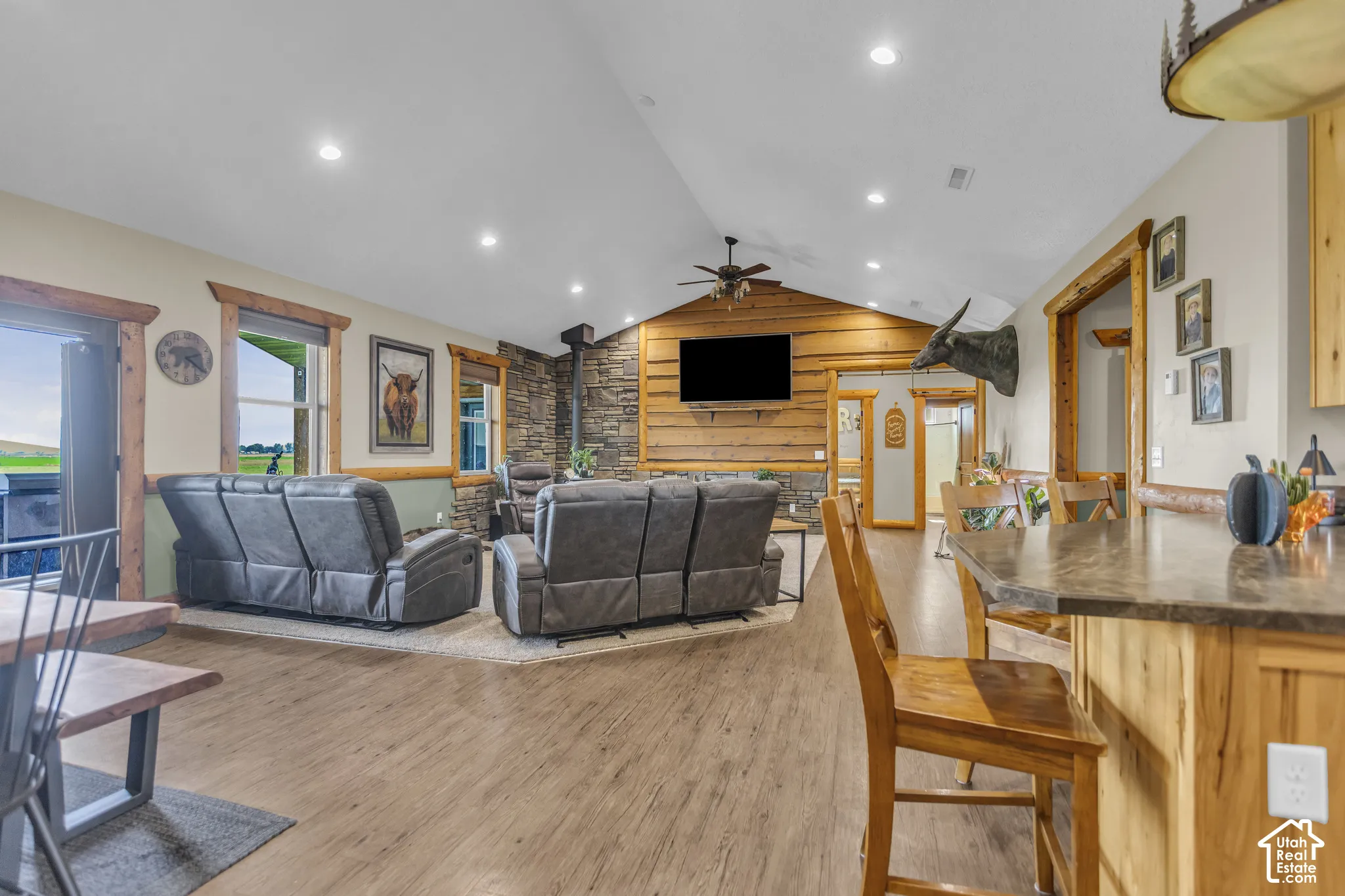 Vaulted ceiling, recessed lighting, wood-finish flooring, stone-clad fireplace, and natural wood trim accents