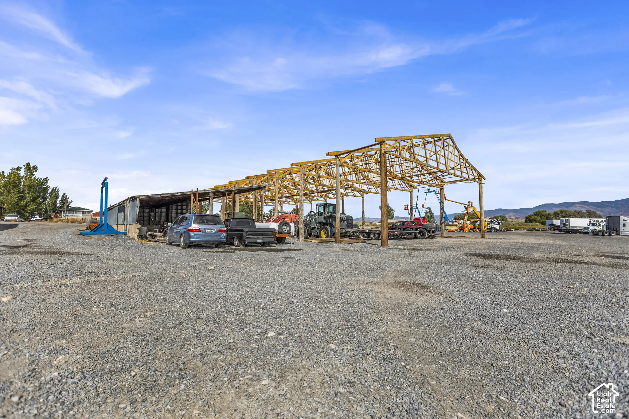 Open-air wood-framed structure, gravel surfacing, and metal-sided outbuilding