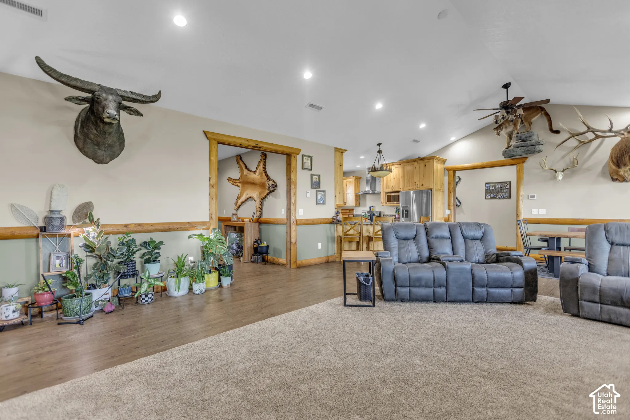 Vaulted ceiling with recessed lighting, wood-finish flooring, two-tone wall treatment, and a cased opening with natural wood trim