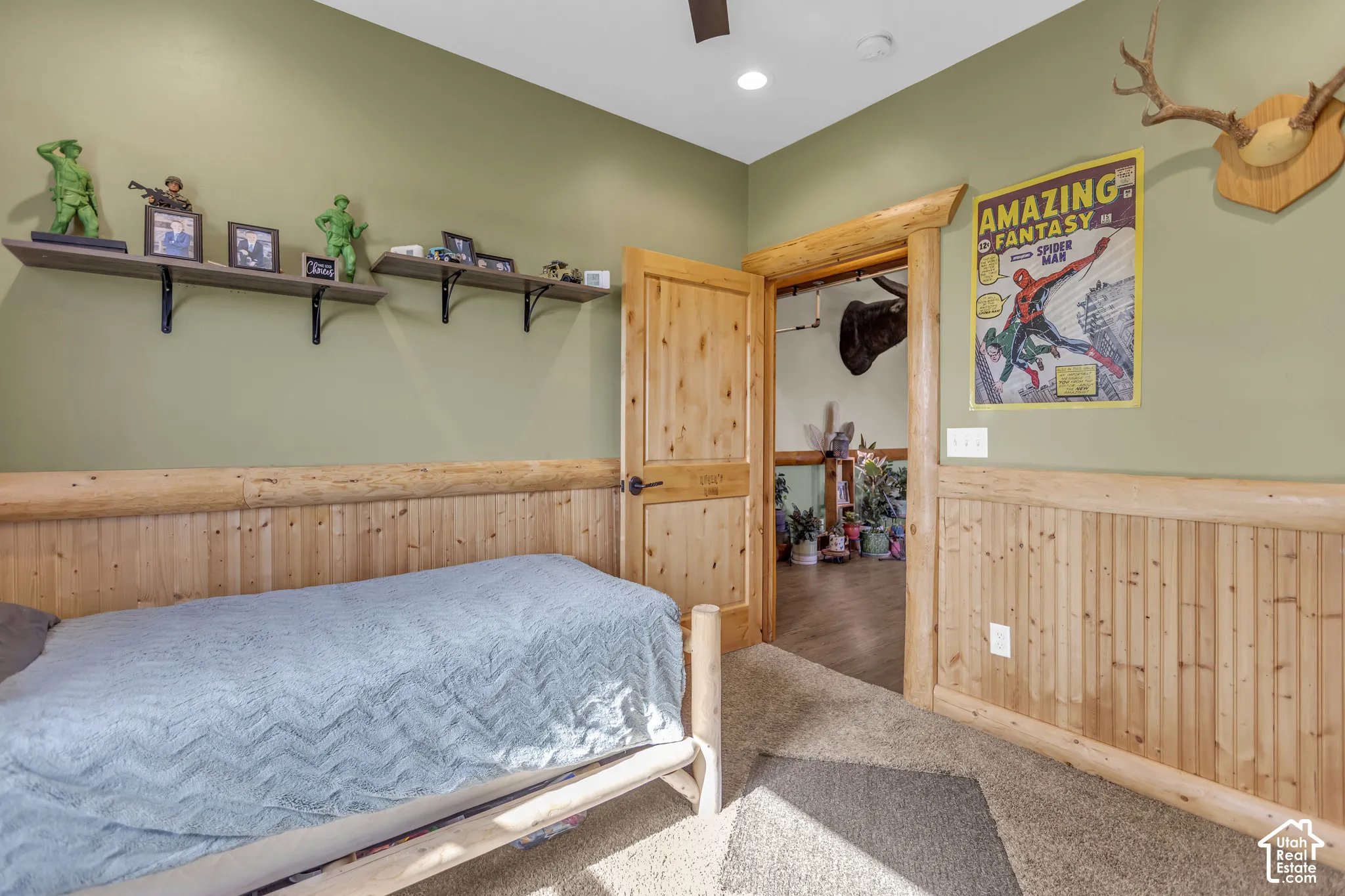 Paneled wood wainscoting with a log trim, wood-finish door with black hardware, and carpeted flooring