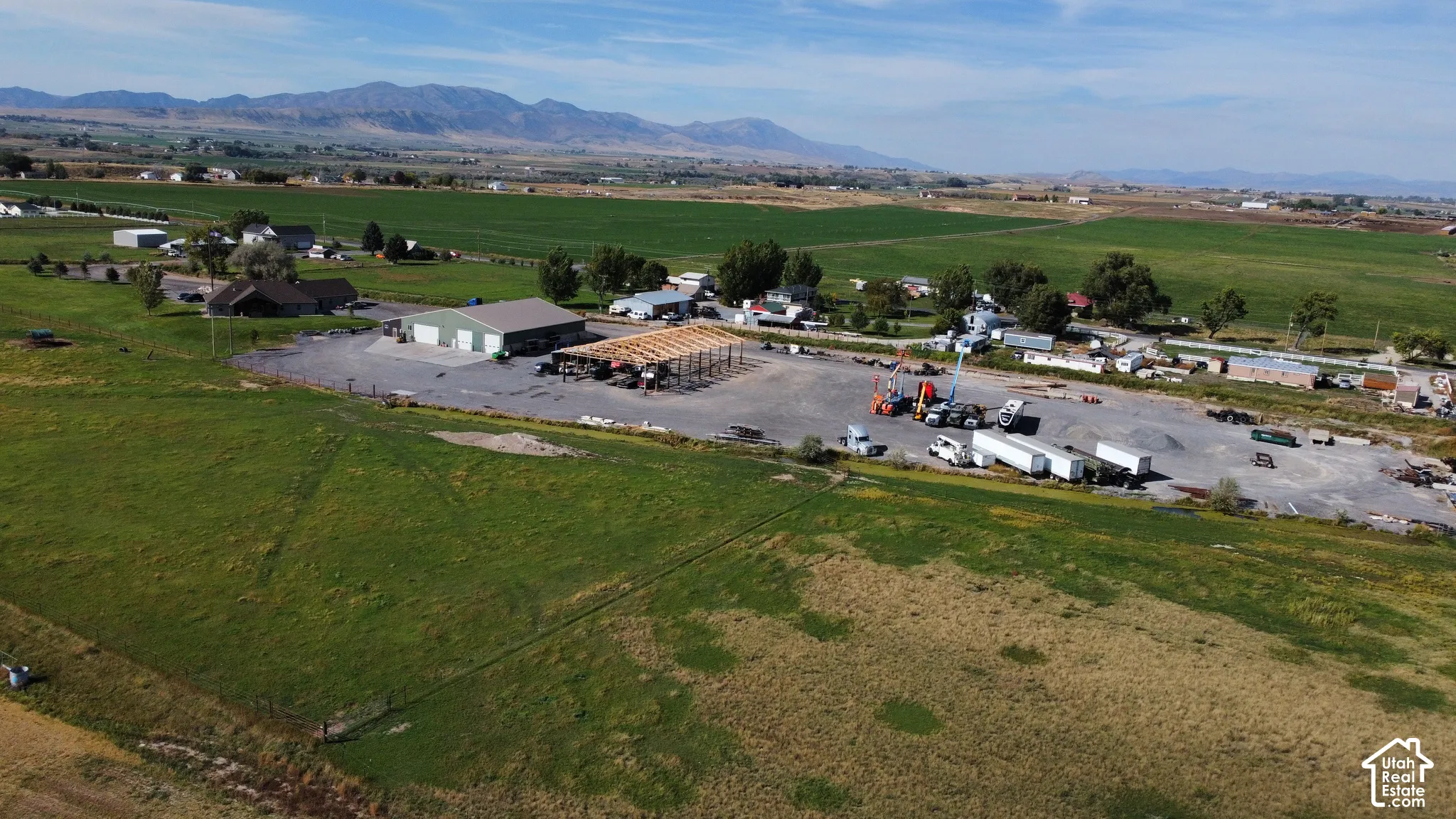 Extensive commercial property featuring multiple buildings, expansive paved and gravel parking areas, and surrounding green spaces